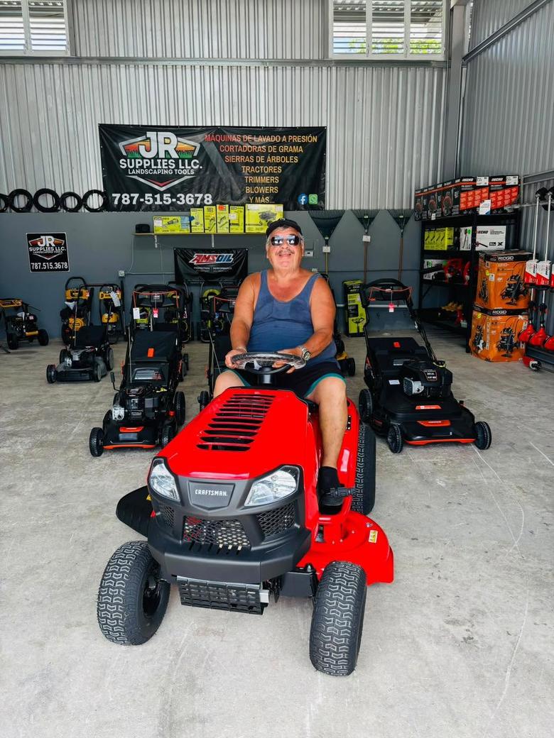 Clienta de JR Supplies sentada en un tractor cortacésped Craftsman rojo dentro de la tienda